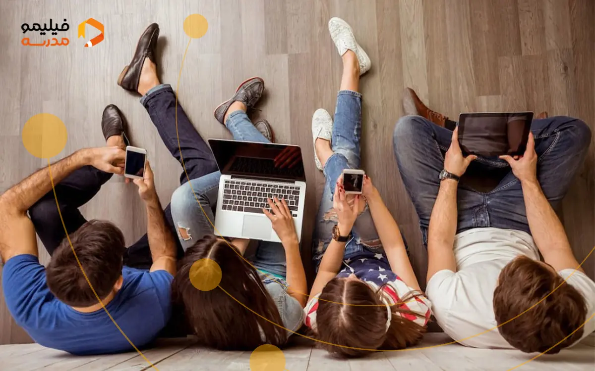 چند نوجوان نشسته روی زمین در حال بازی کردن با موبایل لپ تاپ خود